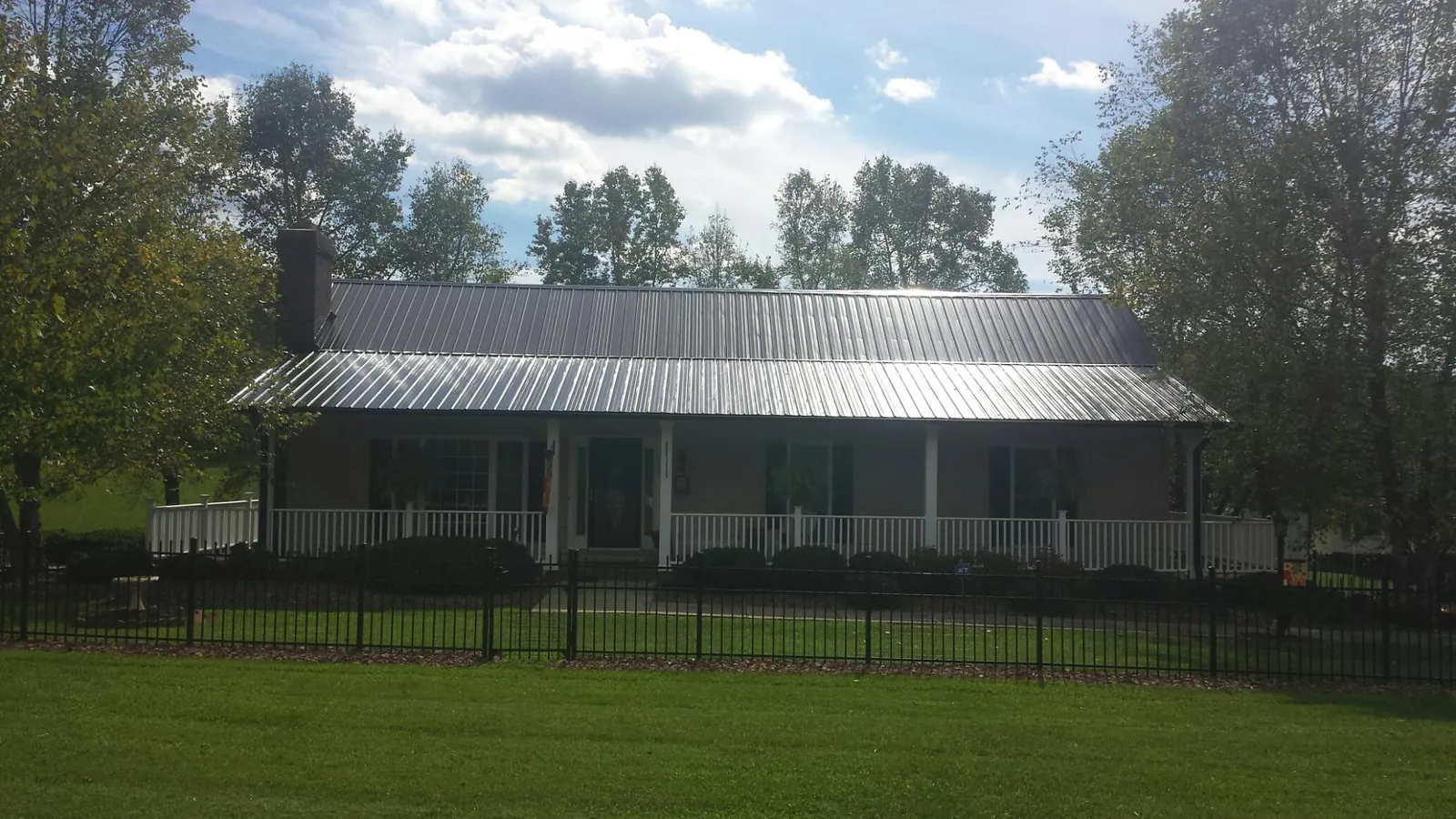Gray metal roof on a brick ranch with a full width front porch — Gutter Guard Installation work by our crew in Sandy